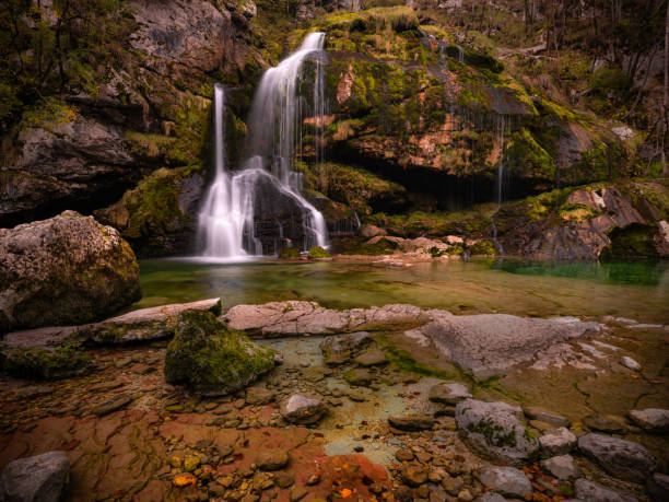 istock Waterfall falling among rocky mountains during autumn day in Slovenia. 1482993532