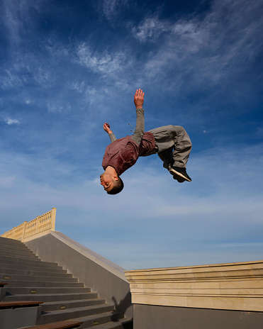 Man doing back somersault. Parkour athlete training in city in sportswear. Free runner jumping have workout. Active lifestyle. Extreme sports, outdoor freerun