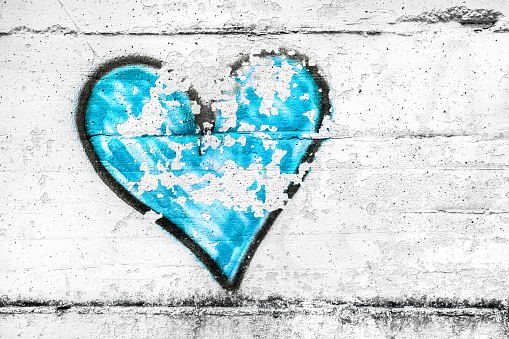 Painted light blue abstract heart shape love symbol, dirty wall background, metaphor to urban and romantic valentine, grunge style.