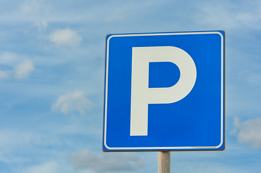 Parking sign on blue cloudy sky with copy space