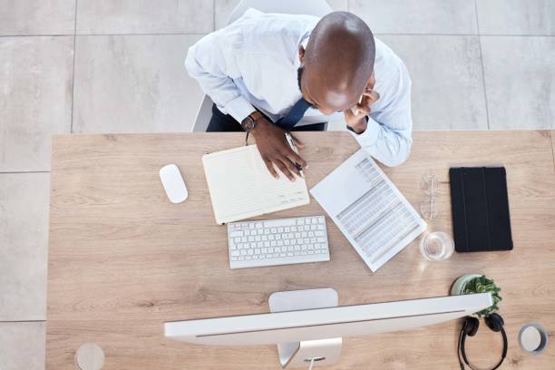 istock Documents, notes and businessman on phone call planning a schedule or growth strategy for a startup in an office. Overhead, employee or black man working in discussion on mobile conversation 1482998172