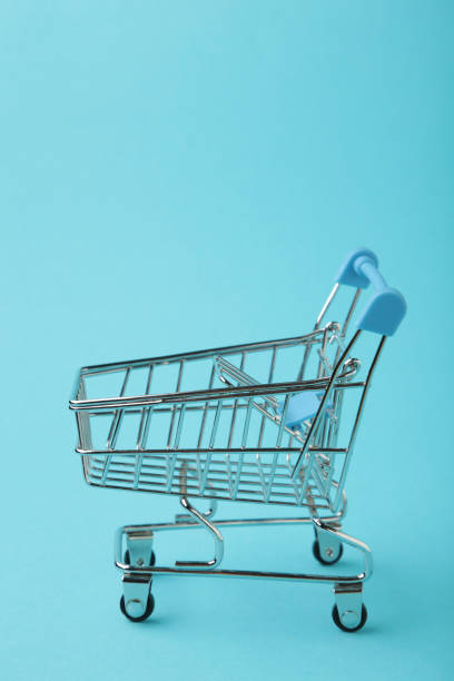 istock Mini shopping trolley on blue background. Vertical photo 1482998286