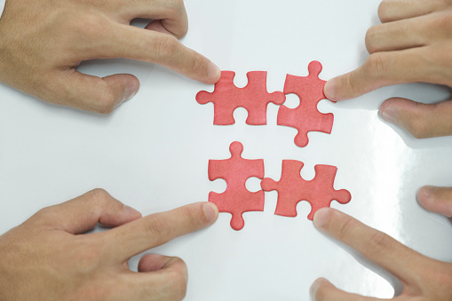 Two persons assembling puzzles together or people working together to find solution of success.