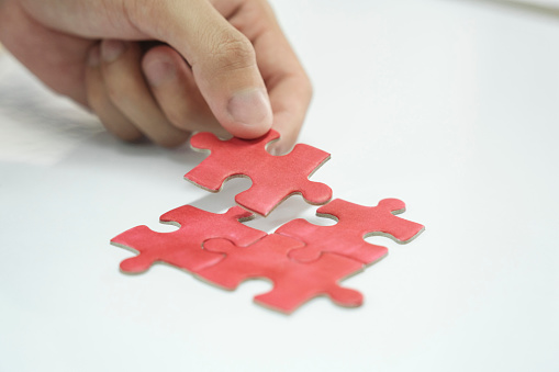 Person assembling puzzles or working to find solution of success to his business. Person completing puzzles, finding answer, and facing challenges.