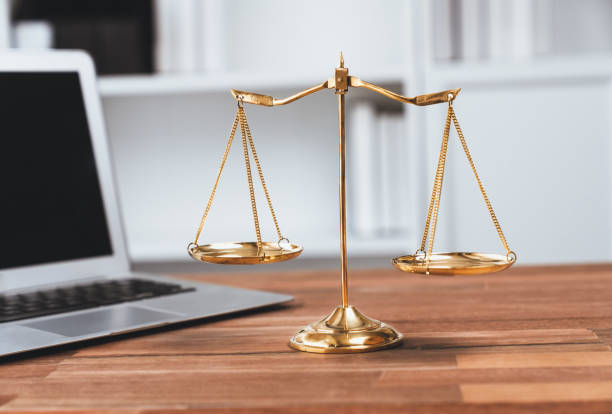 Golden balanced scale on desk with laptop in law office. equility stock photo
