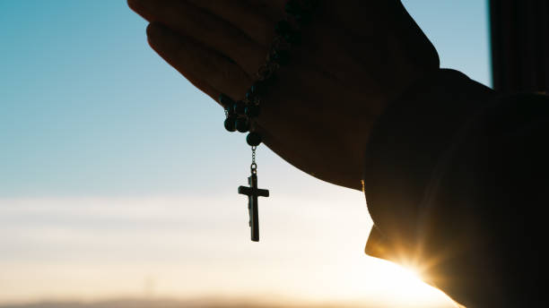 istock Silhouette of praying hands with christian crucifix. 1483002048