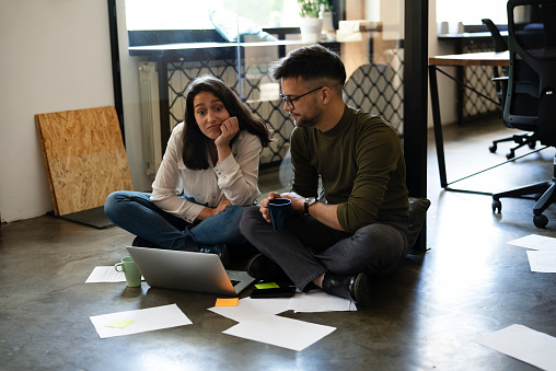 Colleagues sitting on the floor in office. Businesswoman and businessman working on the project