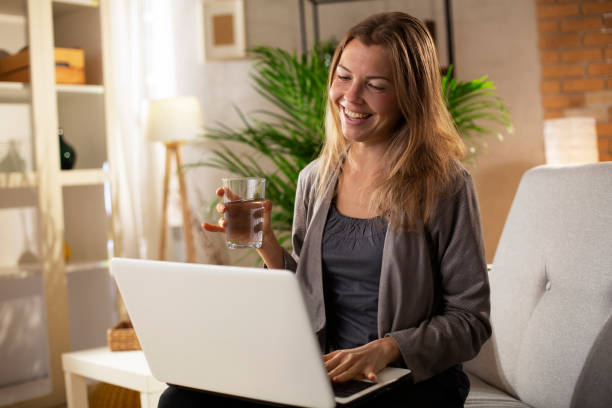 istock Smiling girl drinking water while using the laptop. 1483005829