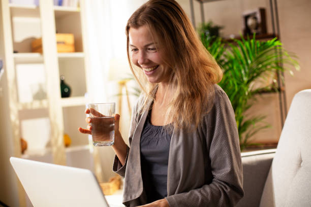 istock Smiling girl drinking water while using the laptop. 1483005841