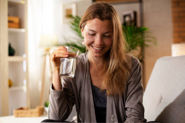 istock Smiling girl drinking water while using the laptop 1483005945