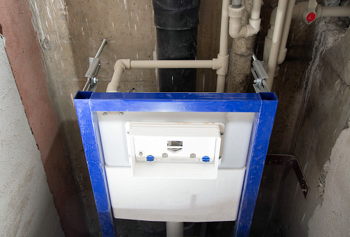 Installation of a new wall-hung toilet with a water drain installation.