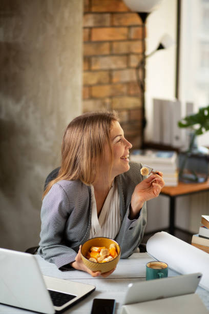 Businesswoman in office having healthy snack stock photo