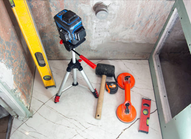 nível de construção a laser, martelo de borracha e ventosa para colocação de azulejos em paredes e pisos. o conceito de reparar e colocar azulejos de grés porcelânico na casa de banho. espaço de cópia para texto - rubber mallet - fotografias e filmes do acervo