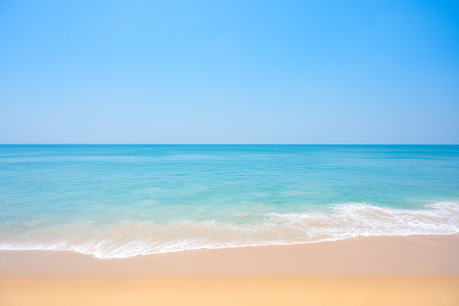 Light blue sea waves on clean sandy beach.