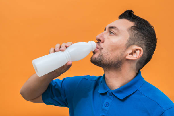 istock Handsome man drinks yogurt or milk on orange background. Mock up copy space 1483015868