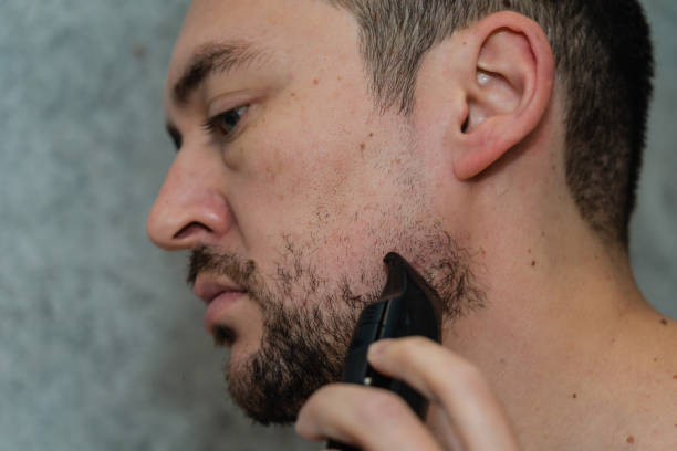 istock Handsome man shaving his beard by electric razor 1483015968