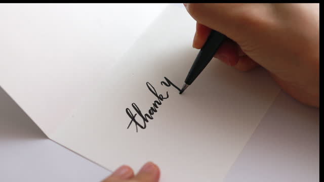 Woman hands writing thank you on a greeting card, preparing a thankful greeting card.