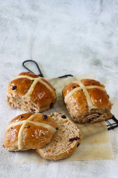 istock Image of homemade Easter hot cross buns on table with wire cooling rack rack, sliced and buttered spiced bun, home baking concept, focus on foreground 1483017111