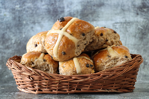 Stock photo showing freshly cooked, homemade Easter hot cross buns, home baking concept.\nThese traditional spiced sweet buns are made and sold over the Easter period, with the cross symbol on the glazed top being made from a flour and water paste, and symbolic to Christianity.