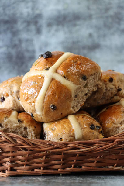 imagem de pães quentes de cruz de páscoa caseiros recém-cozidos em backet de vime de palha marrom, conceito de cozimento caseiro, fundo rosa, foco em primeiro plano - picnic basket christianity holiday easter - fotografias e filmes do acervo