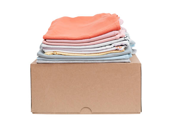 istock Folded stack of clothes on a cardboard box on a white background. Online shopping concept. Delivery of clothes 1483017696