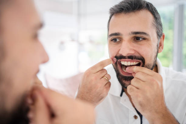 istock Man flossing his teeth in the mirror of a dentist's office 1483018496
