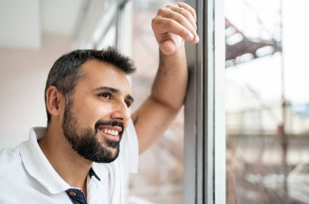 istock Male dentist looking through a window in his office and smiling 1483018533