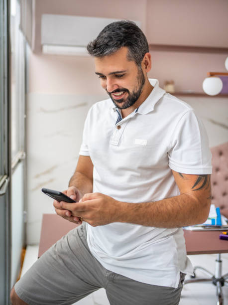 istock Smiling male dentist sending a text message while standing in his office 1483018603