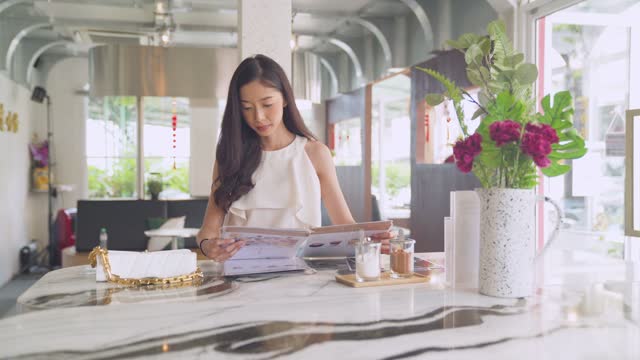 Young woman chilling at cafe, drinking coffee, reading menu