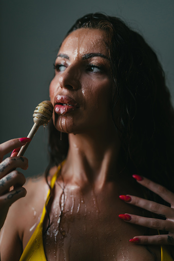 Portrait of a beautiful young woman having a facial mask treatment with honey, studio shot in front of white background