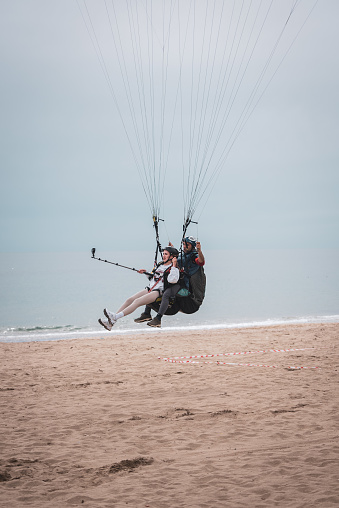 Alanya-Turkey :April 8,2023 Happy couple paragliding landing on the beach .
