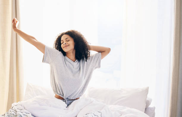 donna nera, stretching mattutino e svegliarsi nella camera da letto di casa dopo aver dormito o riposato. relax, pace e comfort di felice stiramento femminile dopo il sonno sentirsi fresco, sveglio e ben riposato in casa. - wake up stretching women black foto e immagini stock