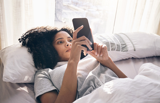 Phone, black woman and typing in home bedroom for social media, texting or internet browsing in the morning. Technology, bed relax and female with mobile smartphone for web scrolling or networking.