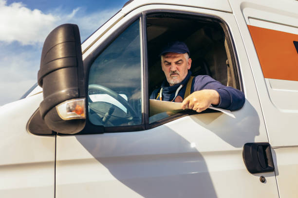 istock Truck driver checking shipment list while sitting in the white cargo van vehicle 1483022139