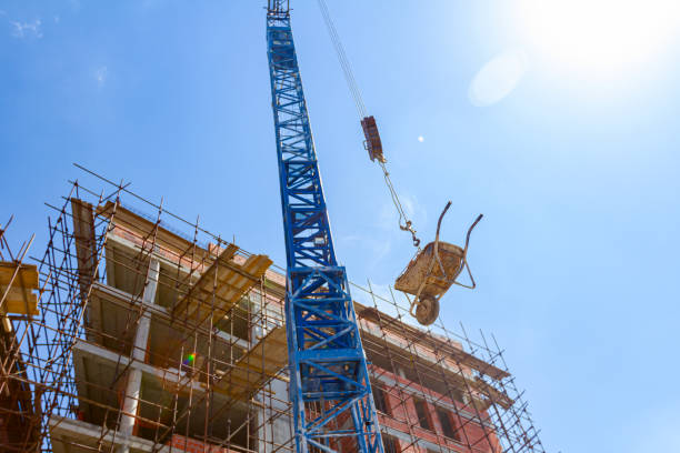 la gru solleva la carriola piena di mattoni rossi, sullo sfondo è un edificio in costruzione, cantiere - scaffolding wheel construction site metal foto e immagini stock