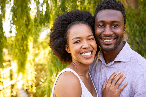 Portrait Of Loving Couple Outdoors Hugging In Garden By Tree At Home