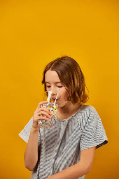 Photo of Pretty teen girl, child with a fresh glass of water isolated