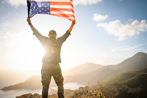 man with american flag on the background of the sea and mountains