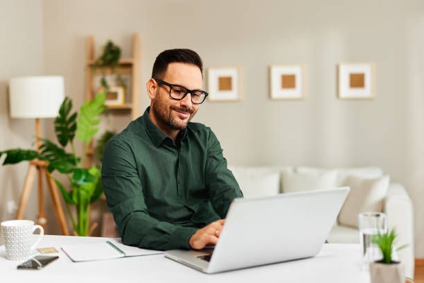 Jeune homme travaillant au bureau avec un ordinateur portable - Photo