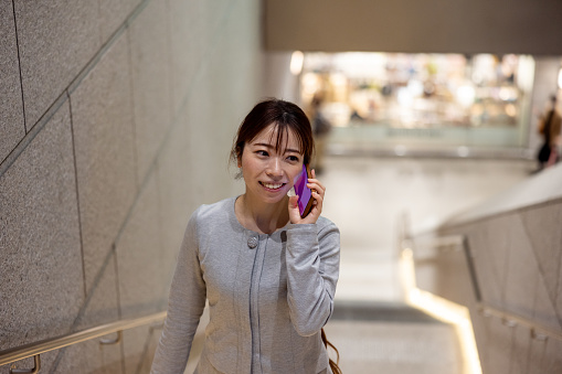 Japanese business woman talking over the phone and walking in city