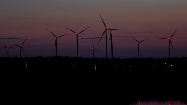 Wind turbines with lights on propeller rotate at night