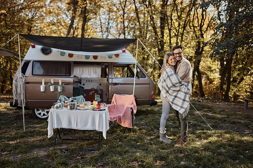 Happy couple in love standing embraced during autumn day at trailer park.