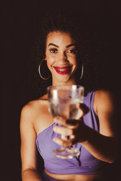 jeune belle femme souriante montrant une tasse en verre. - wall indoors chair floor photos et images de collection