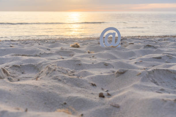 at sign on the beach sand at sunrise - at symbol connection technology community imagens e fotografias de stock