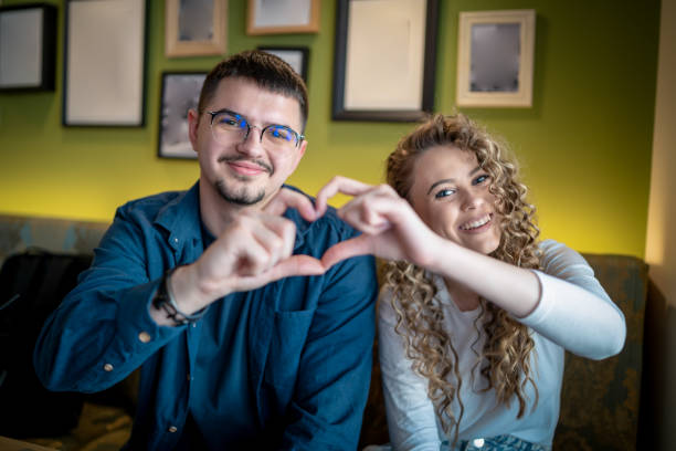 istock couple forming a heart shape with their hands while sitting together 1483037321