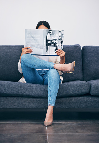Relax, magazine or girl reading newspaper articles on sofa at home for information or story updates. Press, focus or woman relaxing and studying abstract art for knowledge in a publication on couch