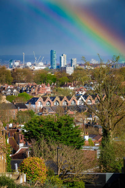 View across city of London from Highgate with rainbow in the sky Panoramic view across the city of London, taking in huge residential districts, with the ultra modern architecture of the skyscrapers of downtown visible on the horizon. There has been a rain shower and a rainbow is vivid in the sky. window chimney london england residential district stock pictures, royalty-free photos & images