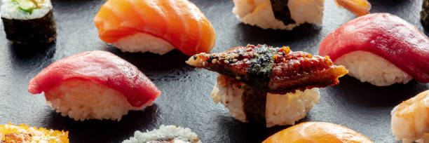 istock Sushi panorama. Nigiri with eel, tuna, salmon on a black background 1483040021