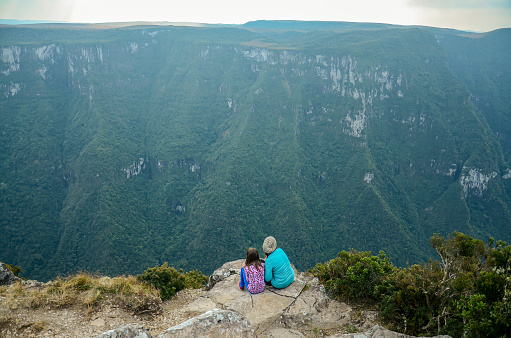 Two young women sitting on the edge of Fortaleza Canyon, in Cambara do Sul, Rio Grande do Sul, Brazil