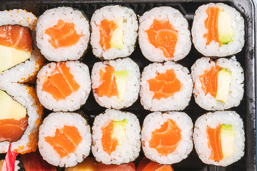 Directly above close up of salmon maki sushi set in a takeout container